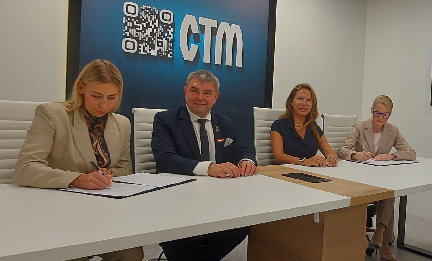 Uroczystość podpisania MoU — przedstawiciele L3Harris i CTM podpisują dokumenty przy stole, w tle logo CTM